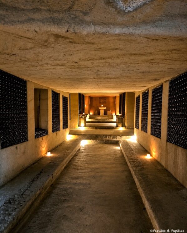 Longue galerie souterraine du Château de La Rivière éclairée par des lumières chaudes
