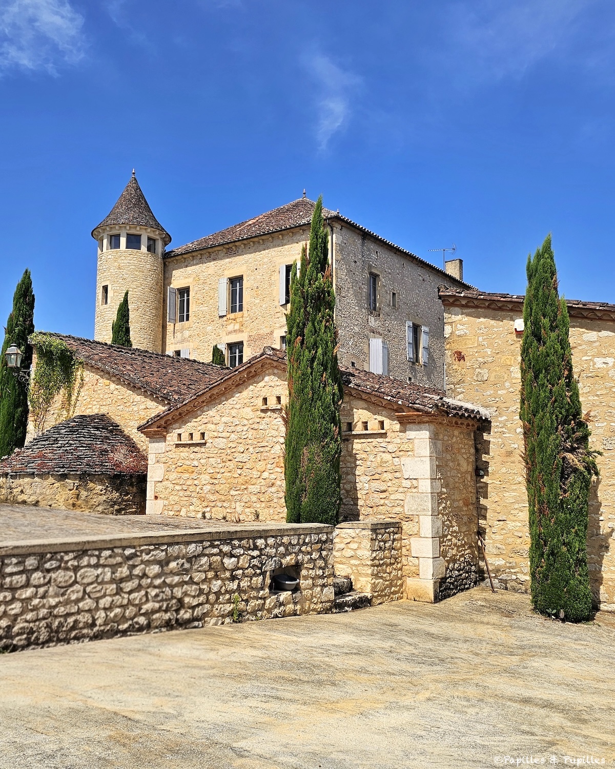 Château de Chambert en pierre blonde sous le ciel bleu