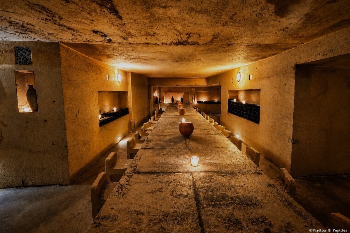 Longue table en pierre dans les caves du Château de La Rivière, éclairée aux bougies